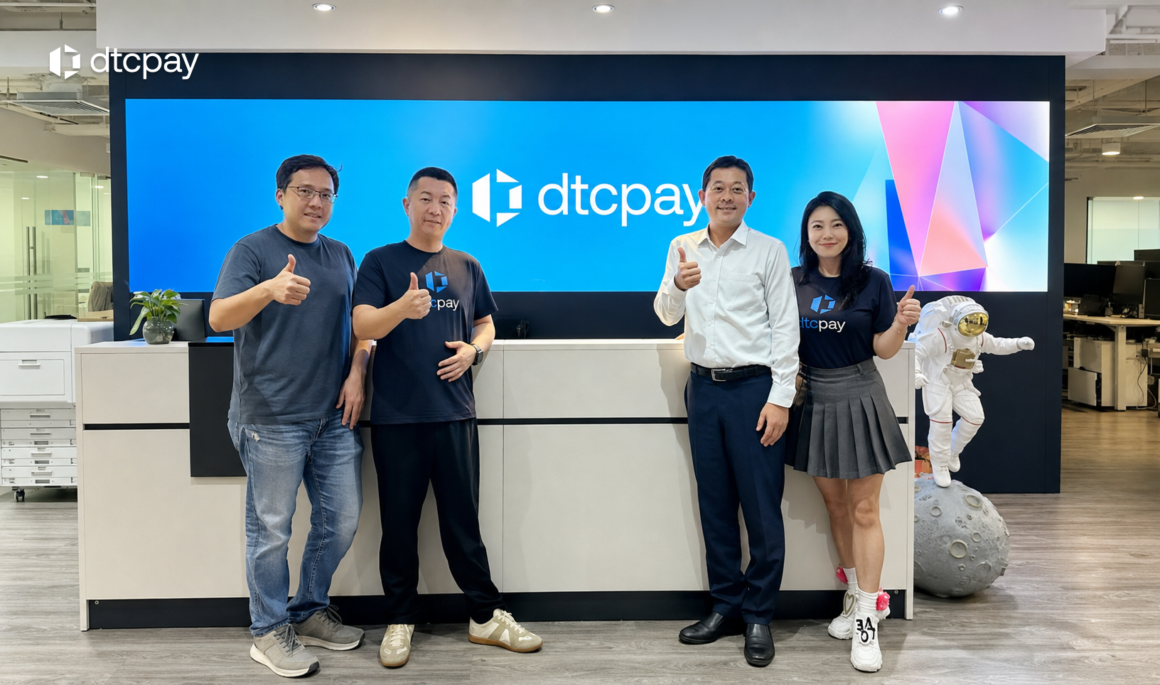 Four people posing in front of the dtcpay logo, accompanying the announcement of SBI Group’s strategic investment in dtcpay’s US$25 million Series A.